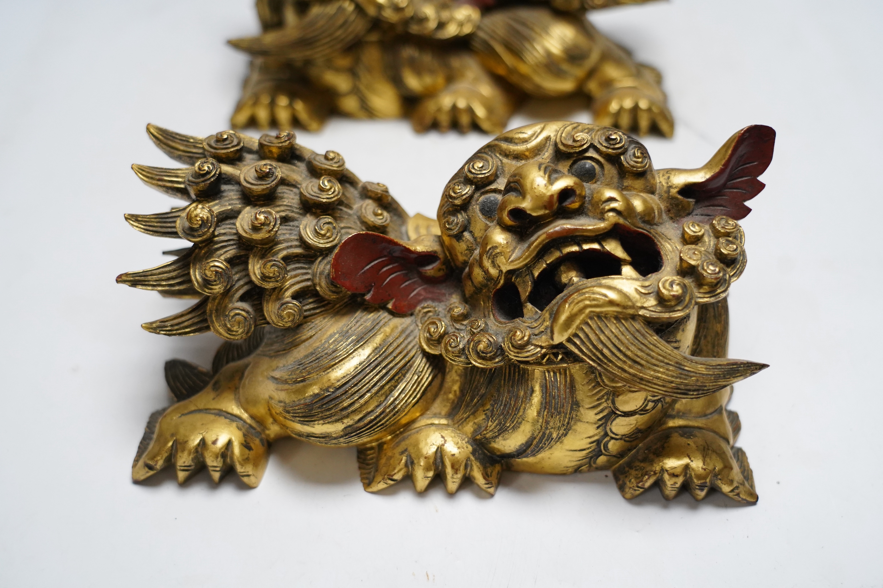 A pair of 20th century Chinese carved giltwood lion mounts, 23cm wide